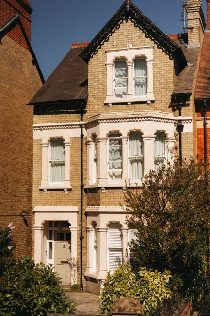 Two professional cleaners from Cleaners Swiss Cottage are engaged in surface cleaning within a modern living room. They are wearing grey shirts and orange overalls, and each is holding a mop, actively